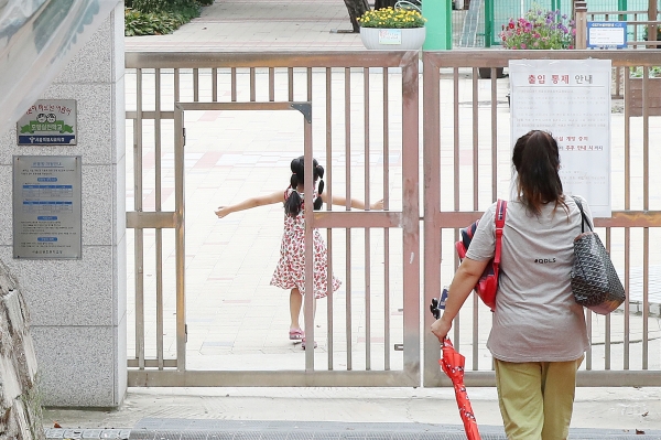 서울의 한 초등학교에서 어머니가 자녀를 오후 돌봄교실에 바래다주고 있다.